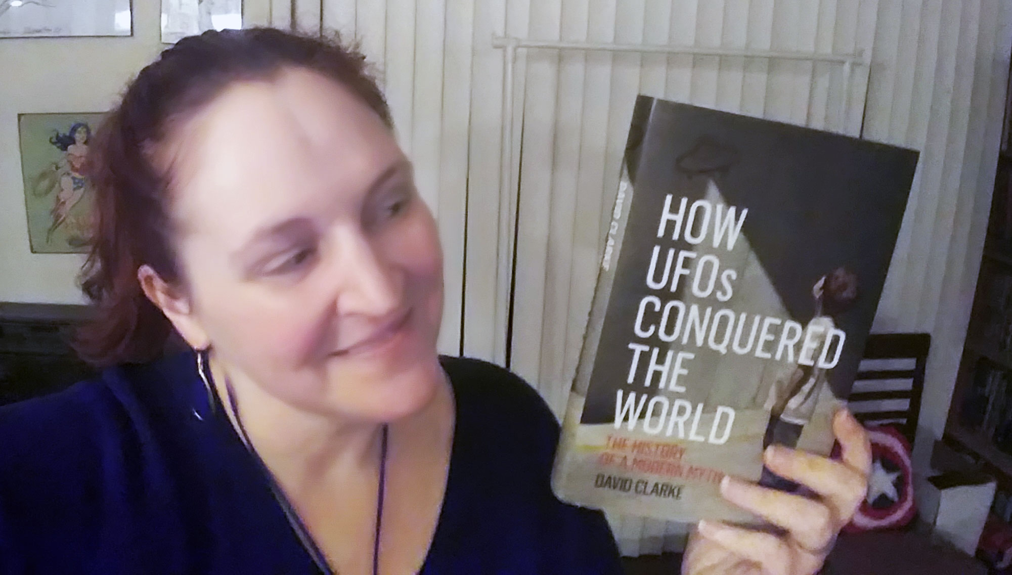 Carma holding a copy of How UFOs Conquered the World
