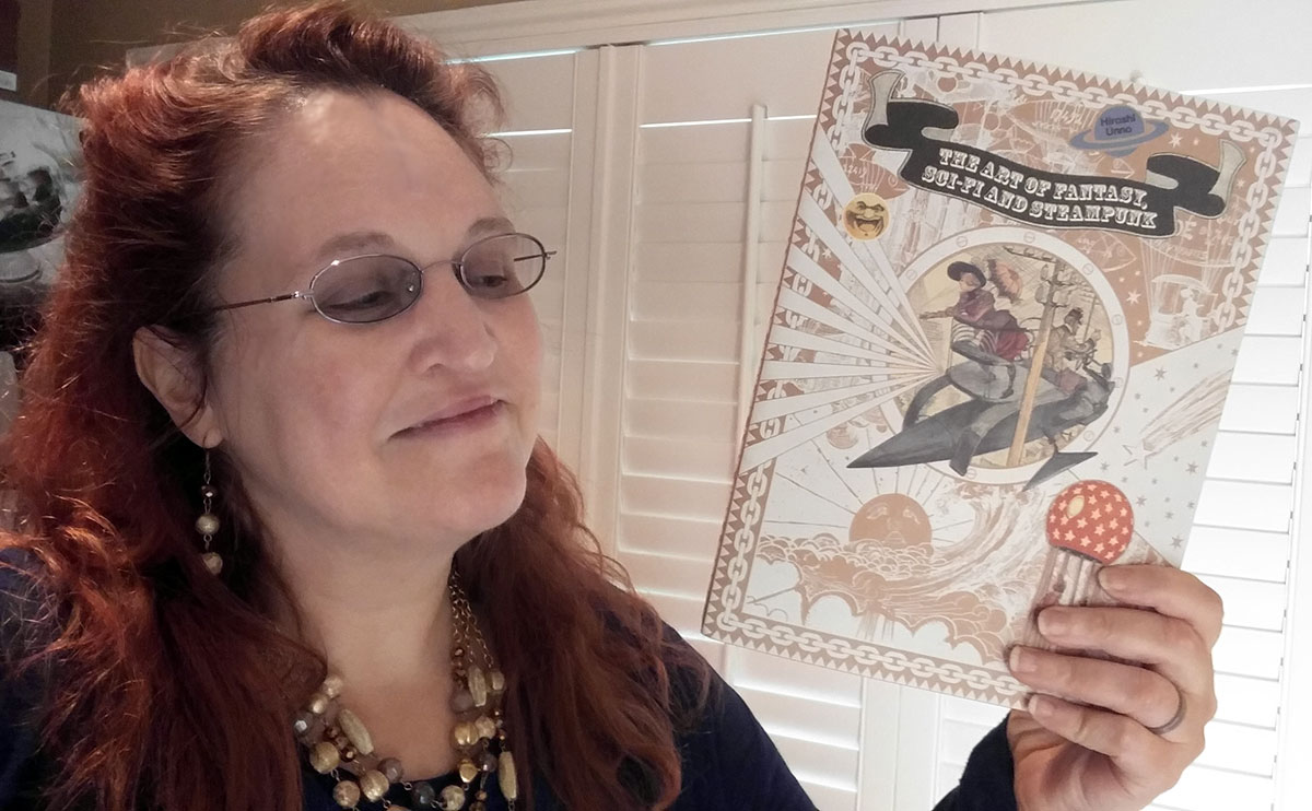 Carma Spence holding a copy of The Art of Fantasy, Sci-fi and Steampunk