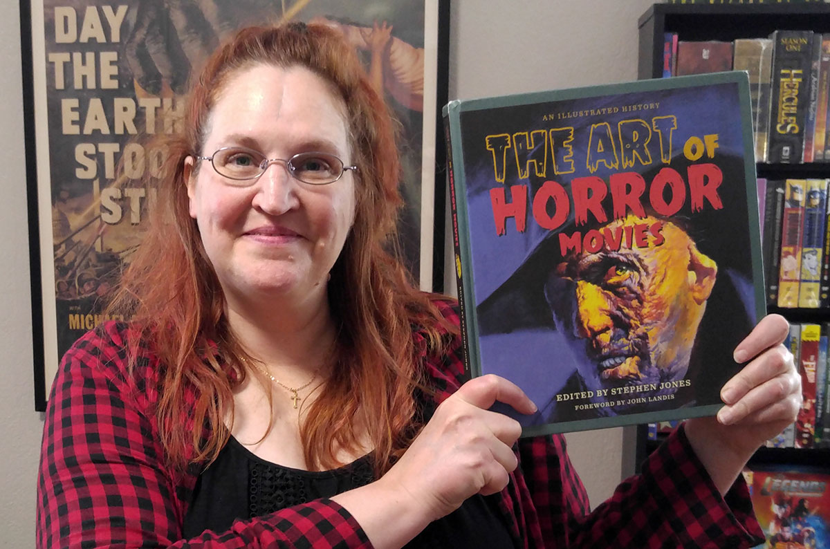 Carma Spence holding a copy of “The Art of Horror Movies” by Stephen Jones