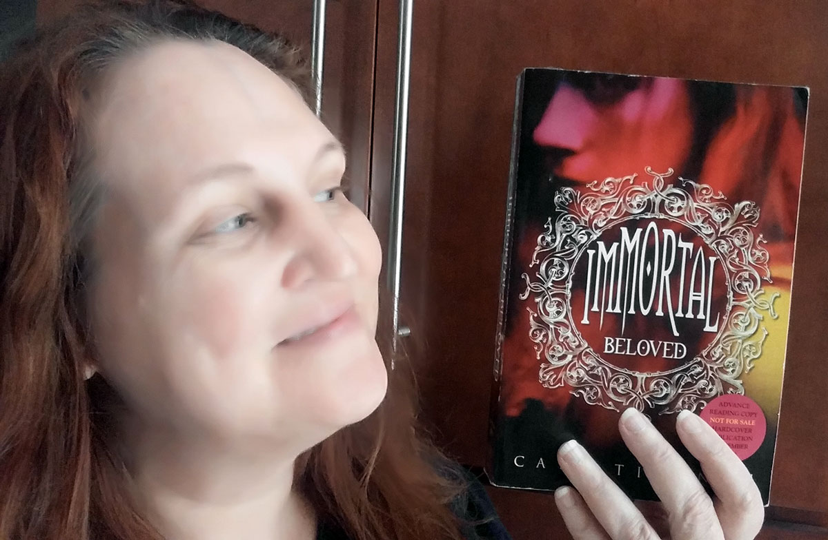 Carma Spence holding an advance reading copy of Immortal Beloved by Cate Tiernan