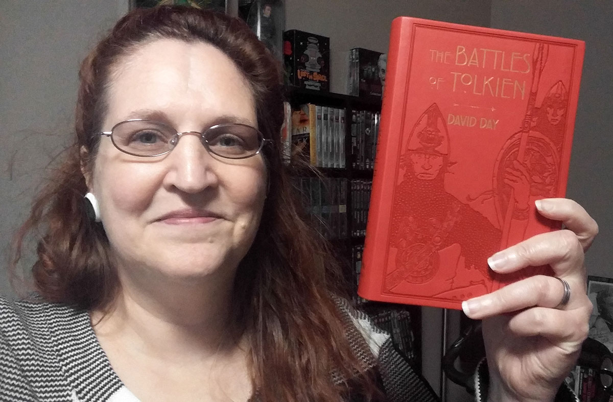 Carma Spence, The Genre Traveler, holding a copy of The Battles of Tolkien by David Day