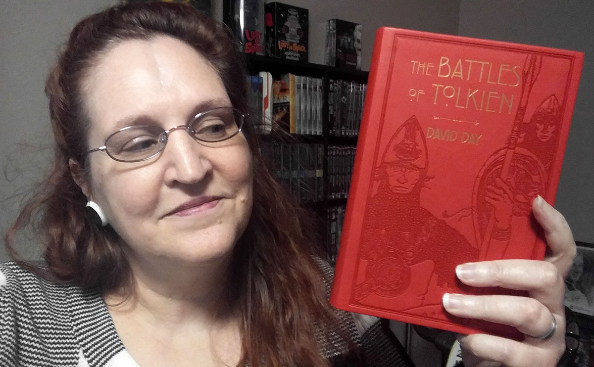 Carma Spence, The Genre Traveler, holding a copy of The Battles of Tolkien by David Day
