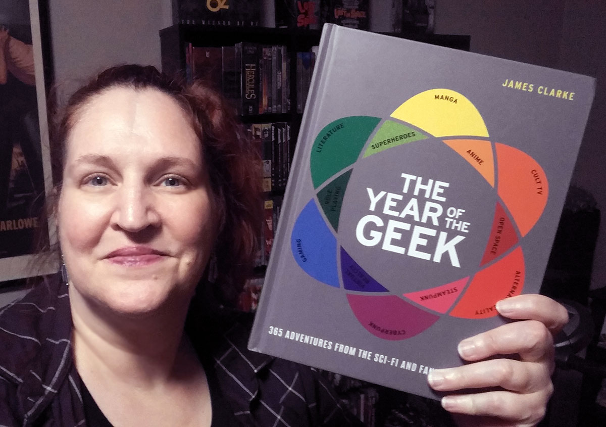 Carma Spence holding a copy of The Year of the Geek by James Clarke
